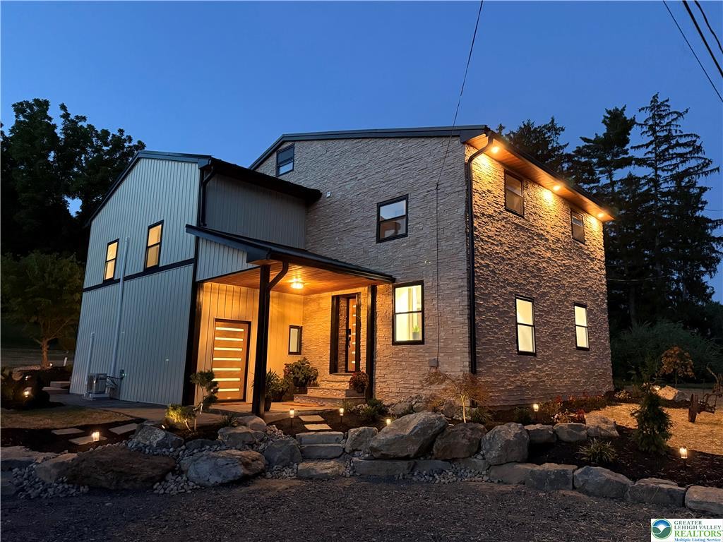A modern home at dusk with new stone and siding work by Grateful Guys Contracting